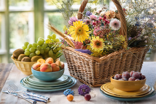 Basket of flowers with bowls of fresh fruit on a sunlit table