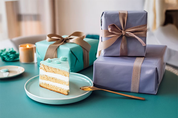 Stacked pastel wedding gifts with flowers and a slice of cake